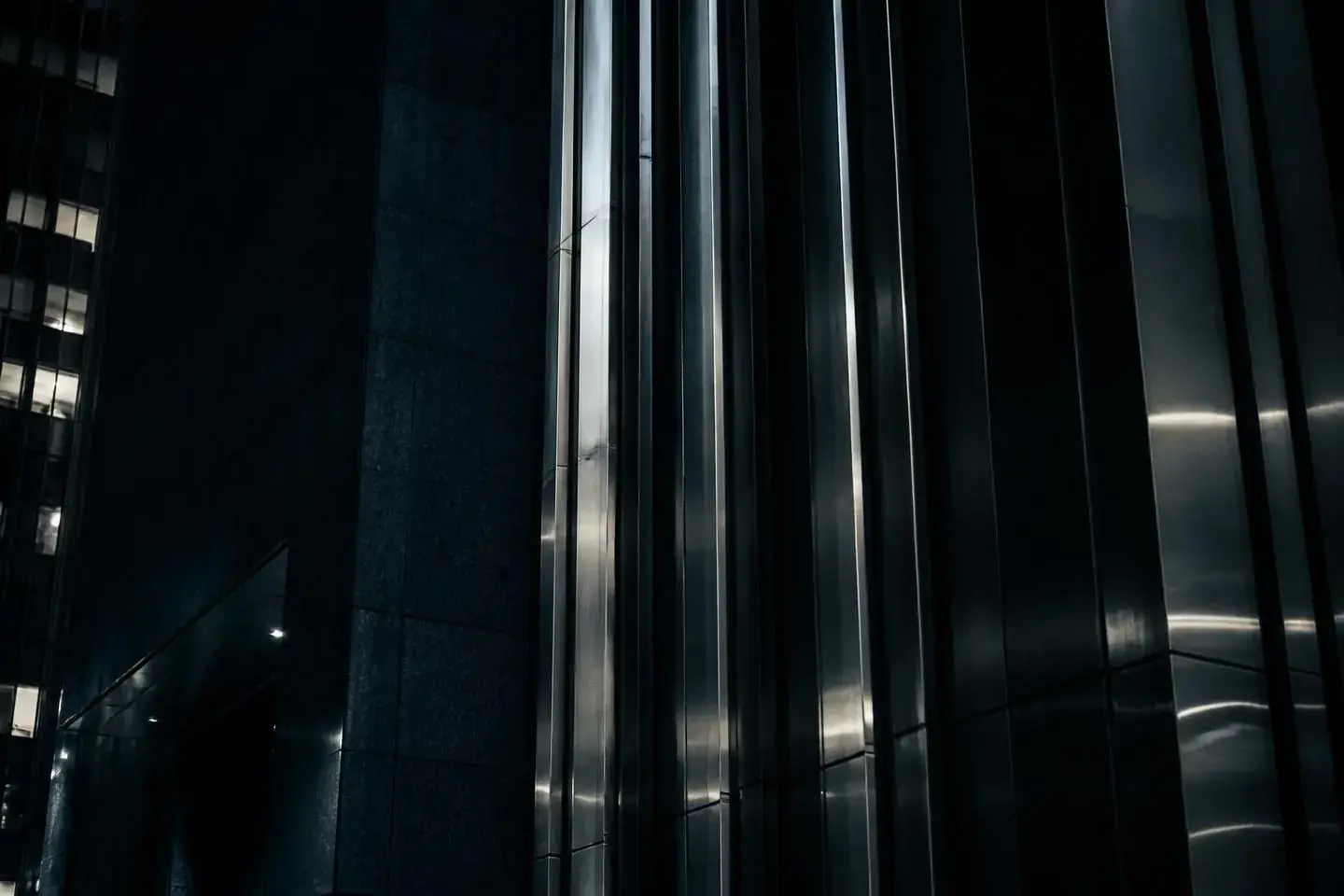 Dark steel and stone facade of a financial headquarters at night